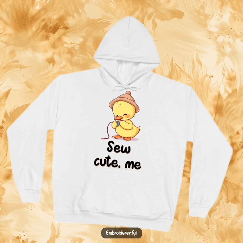 Funny hoodie depicting a cute duck in a small hat struggling to sew a button, offering warmth and whimsical charm.
