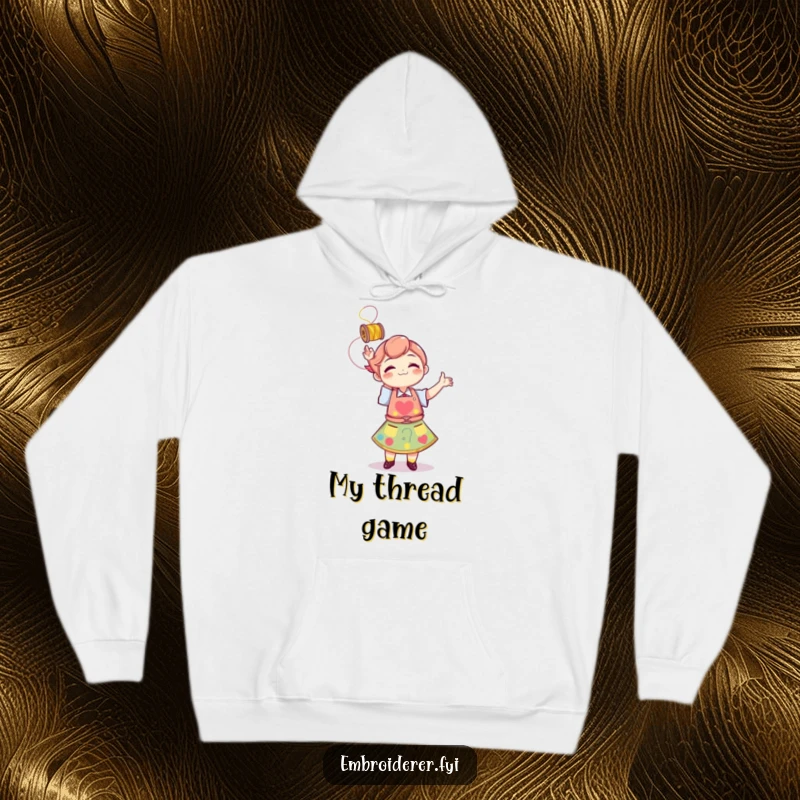 Funny, cozy hoodie featuring a character in an apron tossing thread, symbolizing creative playfulness and warmth.